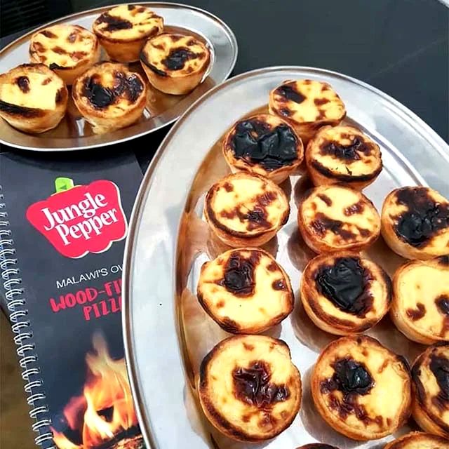 Trays of freshly baked pastéis de nata next to the Jungle Pepper menu
