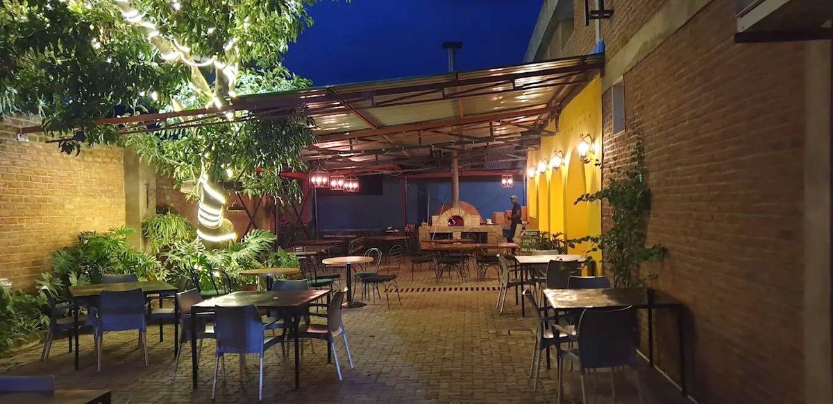 Jungle Pepper courtyard at night, string lights and the glowing wood-fired oven